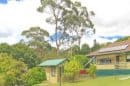A house surrounded by lush green trees and a garden in Upwey, Victoria.