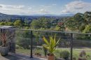 View from a balcony overlooking lush green trees and rolling hills in Victoria.