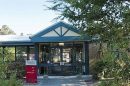 Entrance to a park or community centre with trees and a blue-roofed building in Dandenong Ranges.