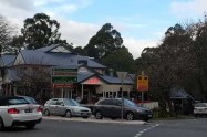 Street scene with cars and a cafe in a wooded area of the Dandenong Ranges.