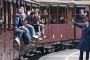 People boarding a vintage train at a station in a forested area in Victoria.